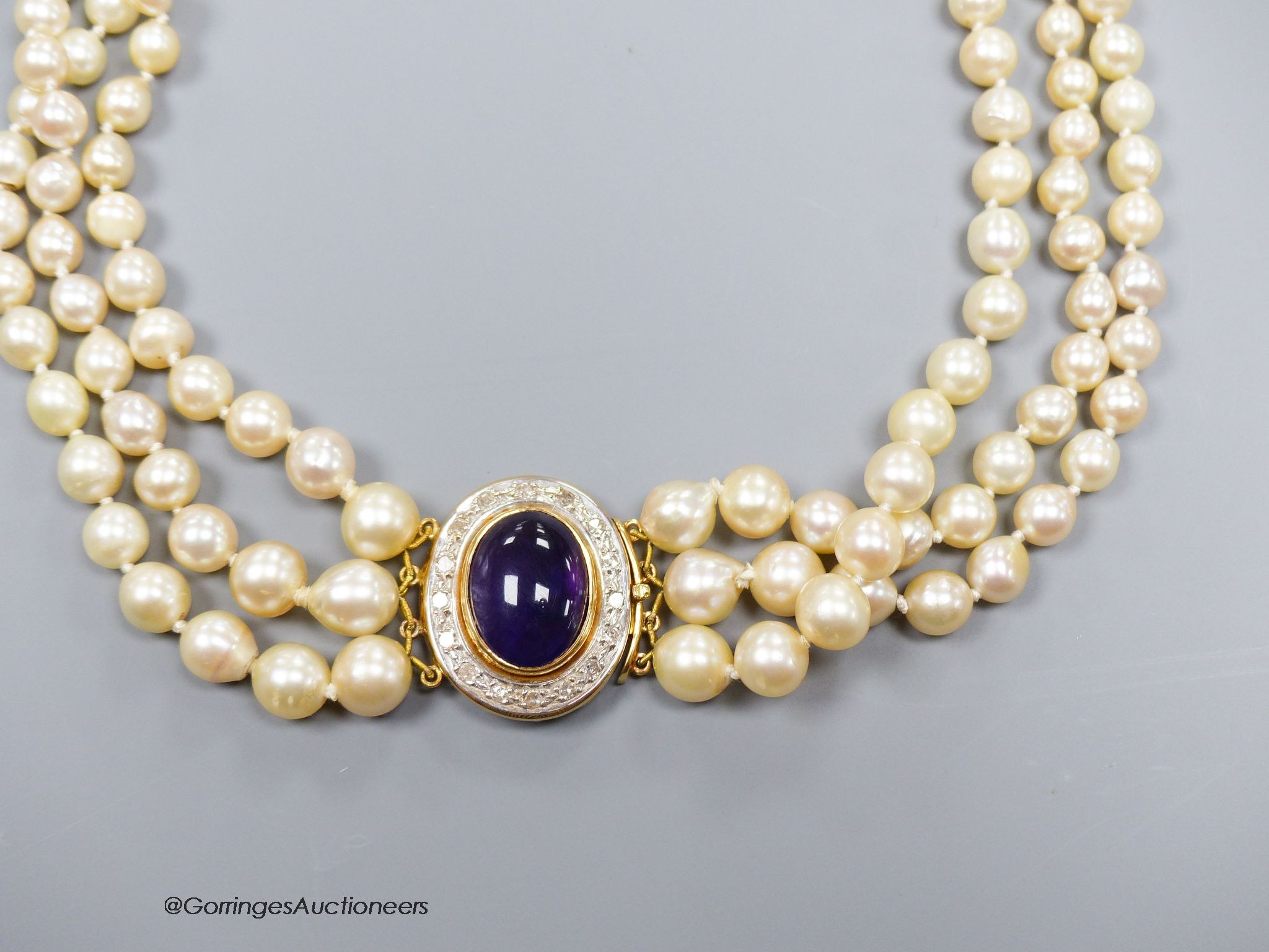 A three strand cultured pearl necklace with cabochon amethyst and diamond set 18ct gold clasp, 40cm.